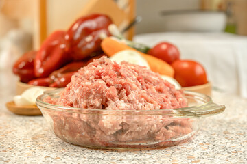 Raw minced meat in front of peeled vegetables for cooking.