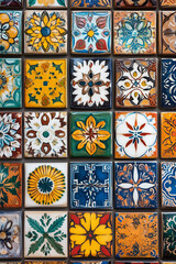 Brightly colored tiles with traditional patterns. Arranged neatly on the wall, each tile is painted with a unique design.