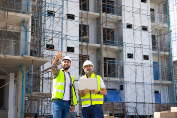 Architect and contractor working on building in construction site. Two Professional Architects Engineer Working on Personal laptop computer at house construction site