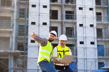 Architect and contractor working on building in construction site. Two Professional Architects Engineer Working on Personal laptop computer at house construction site