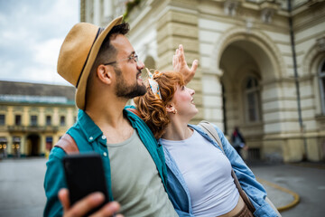 Young couple, on a vacation, exploring the new city and using their phone as gps to help them not...