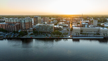 Aerial view of historic downtown Wilmington, NC, with buildings reflecting the sunrise over the Cape Fear River.