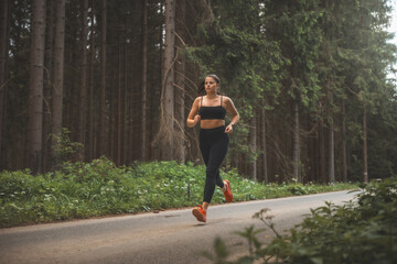 Brunette aged 20-25 in black sportswear running in nature in the evening sun. Active lifestyle. Outdoor sport