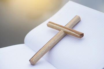 Wooden cross on white paper notebook. Concept, Christian worship. Faith, forgiveness, belief, love, hope, peace and happiness. Crucifix, religious symbol of Christianity.         