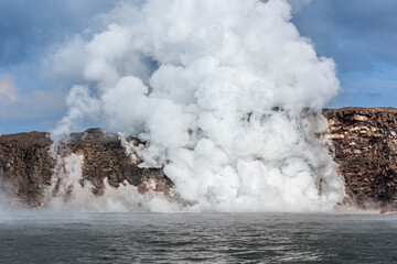 Lava tube flowing into ocean in Hawaii at dawn shows the hot steam as the lava hits the waters of the island