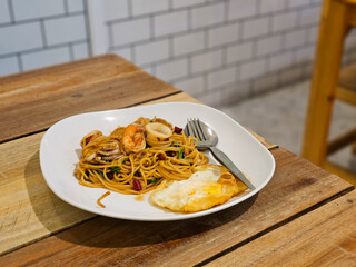 Seafood spaghetti is pasta tossed with a rich sauce, shrimp, and squid, offering a spicy, garlicky flavor.