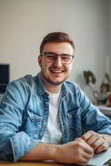 Fototapeta premium Man wearing glasses seated at desk in office environment with blurred background.