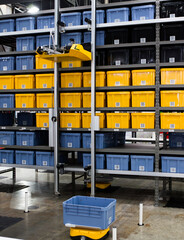 Autonomous robot picking materials from multi-layer rack in modern industrial warehouse.