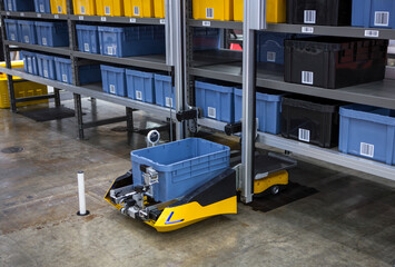 Autonomous robot picking materials from multi-layer rack in modern industrial warehouse.