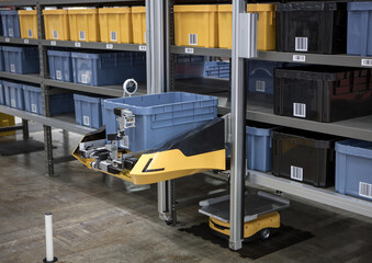 Autonomous robot picking materials from multi-layer rack in modern industrial warehouse.