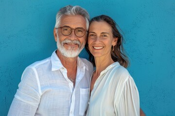 Happy mature couple standing together against blue background.