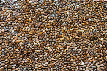 Large natural pebbles arranged to decorate beautiful and strong wall. Yellow and brown pebble stone wall. Surface and Texture background of round stone wall to use as wallpaper. lot of natural stone.