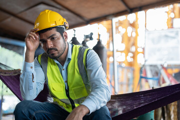 Asian man worker feeling tired while sitting at construction site.