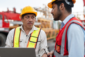 Two civil engineer in safety vests and helmets using a tablet for planning to install tower crane...