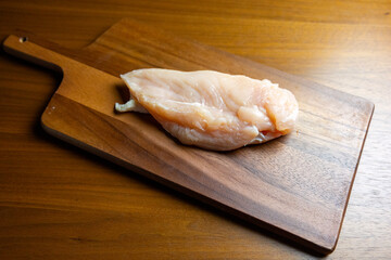 木製のカッティングボードの上の鶏むね肉