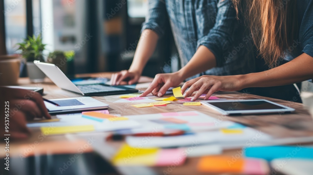 Poster Close-up of a team collaborating with sticky notes and digital devices during brainstorming. Business planning and teamwork in a modern office.