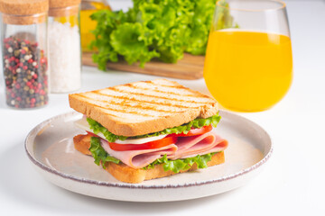 Close-up of two sandwiches with bacon, salami, prosciutto and fresh vegetables on rustic wooden cutting board. Club sandwich concept