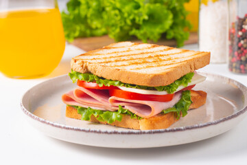 Close-up of two sandwiches with bacon, salami, prosciutto and fresh vegetables on rustic wooden cutting board. Club sandwich concept