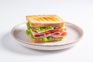 Close-up of two sandwiches with bacon, salami, prosciutto and fresh vegetables on rustic wooden cutting board. Club sandwich concept