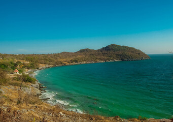 Aerial panorama of Thailand's verdant, with blue and aquamarine the sea, and clouds shining by sunlight in the background.