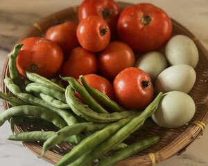 Close up of Basket of local produce from farmers market, green beans, tomatoes and duck eggs