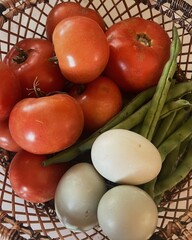 Close up of Basket of local produce from farmers market, green beans, tomatoes and duck eggs
