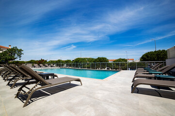 Fototapeta premium Modern poolside retreat with sun loungers in a serene urban setting