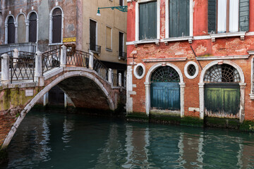 Venice Canal With Bridge And Aged Doors In Italy