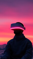 Person wearing a futuristic VR headset at sunset, enjoying virtual reality experience against a vibrant pink and purple sky.