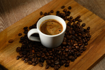 Arrangement of coffee cup and roasted coffee beans on rustic wooden background.