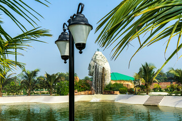 Elegant street lamp on the background of palm branches, pool and waterfall.