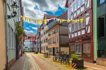 Fototapeta premium Quiet street with half-timbered houses and festive decorations in Marburg, Germany, on a cloudy day