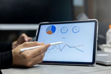 close up manager of marketing department use stylus pen to write or check summary profit report and performance of company on tablet in meeting office room for finance and roi of business concept