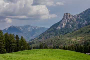 Majestic mountain landscape with rolling hills and dense forests under a cloudy sky in summer