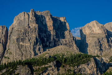 Majestic mountain range under clear blue sky with rugged cliffs and lush greenery in summer sunlight