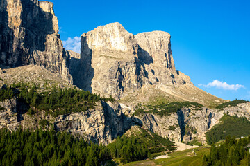 Majestic Dolomite mountain range under a clear blue sky in summer showcasing rugged terrain and lush greenery