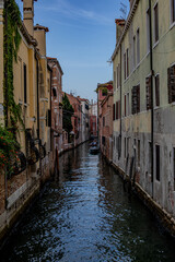 Canal winding through narrow streets lined with historic buildings in Venice during a clear day