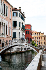 A charming canal with colorful buildings and a stone bridge in a quiet Venetian neighborhood during the late afternoon