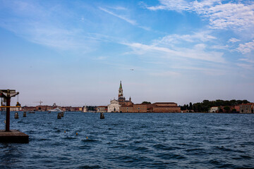Fototapeta premium A serene view of the Venetian skyline featuring historic buildings and waterway activities under a clear blue sky