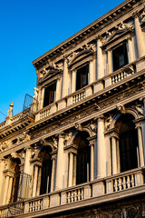 Historic architectural details of a grand building in Venice, showcasing ornate columns and decorative elements under a clear blue sky