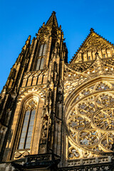 St. Vitus Cathedral's intricate Gothic architecture highlighted by sunlight in Prague during late...