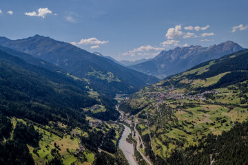 Stunning aerial view of a valley with a winding river surrounded by mountains on a clear day in Switzerland