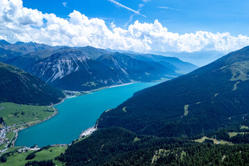 Aerial view of a serene alpine lake surrounded by majestic mountains on a sunny day in the Swiss Alps
