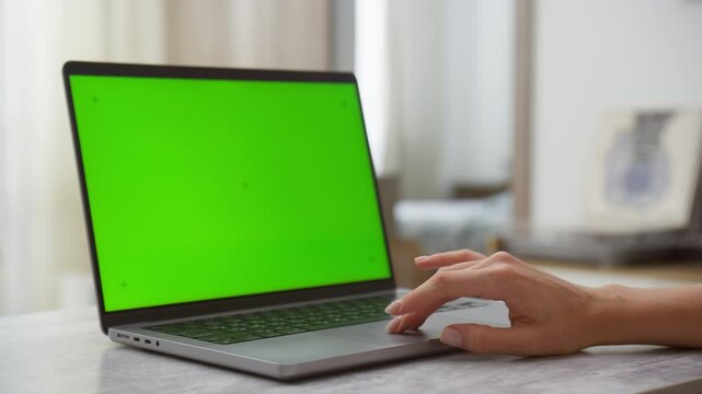 Laptop with green screen chroma key and hand on trackpad