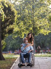 Woman pushing man in wheelchair in park