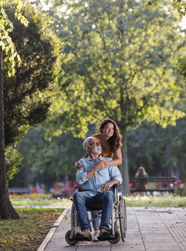 Woman pushing man in wheelchair in park