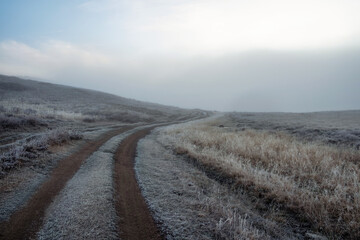 Morning dirt road through the foggy mountain plateau.