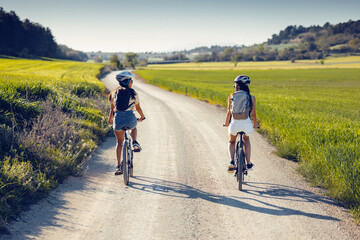 cheerful women friends cycling through rapessed field