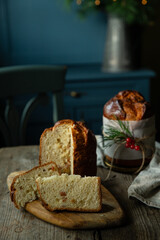Two homemade Christmas panettone , one cut and the other whole, on wooden table on rustic kitchen with blue furniture.