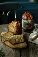 Two homemade Christmas panettone , one cut and the other whole, on wooden table on rustic kitchen with blue furniture.